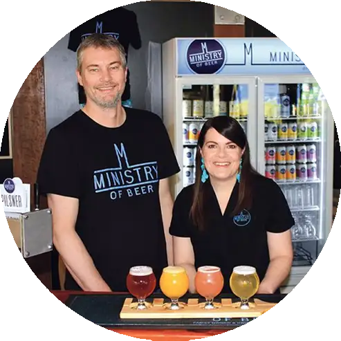 Brett and Dayna from Ministry of Beer standing behind a beer tasting paddle at their Barossa Valley brewery.