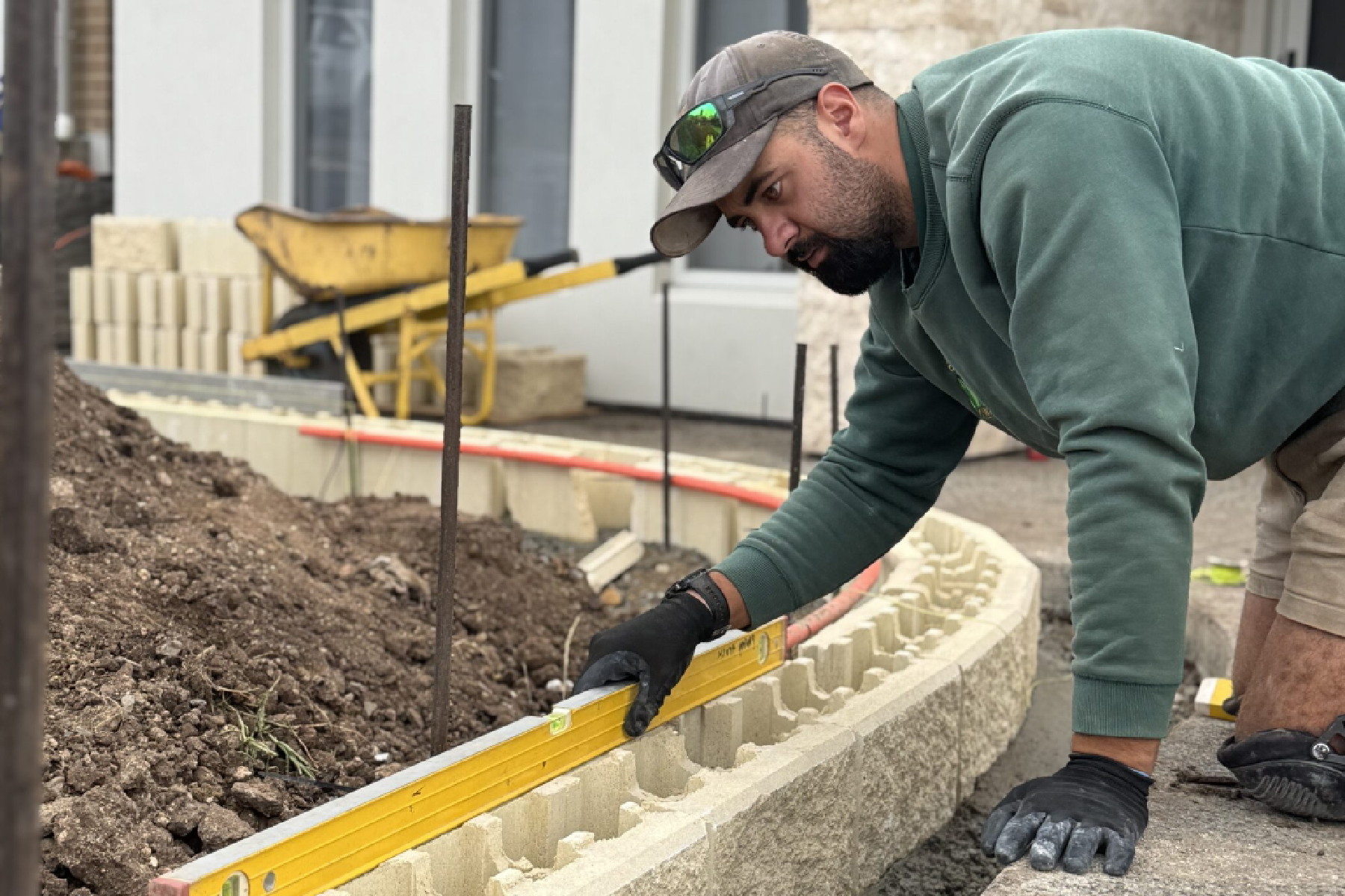 Landscaper checking level on curved retaining wall blocks in Adelaide.
