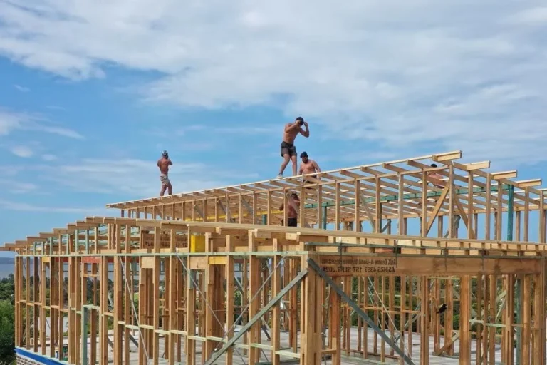 Crew constructing timber roof trusses on a multi‑storey frame.